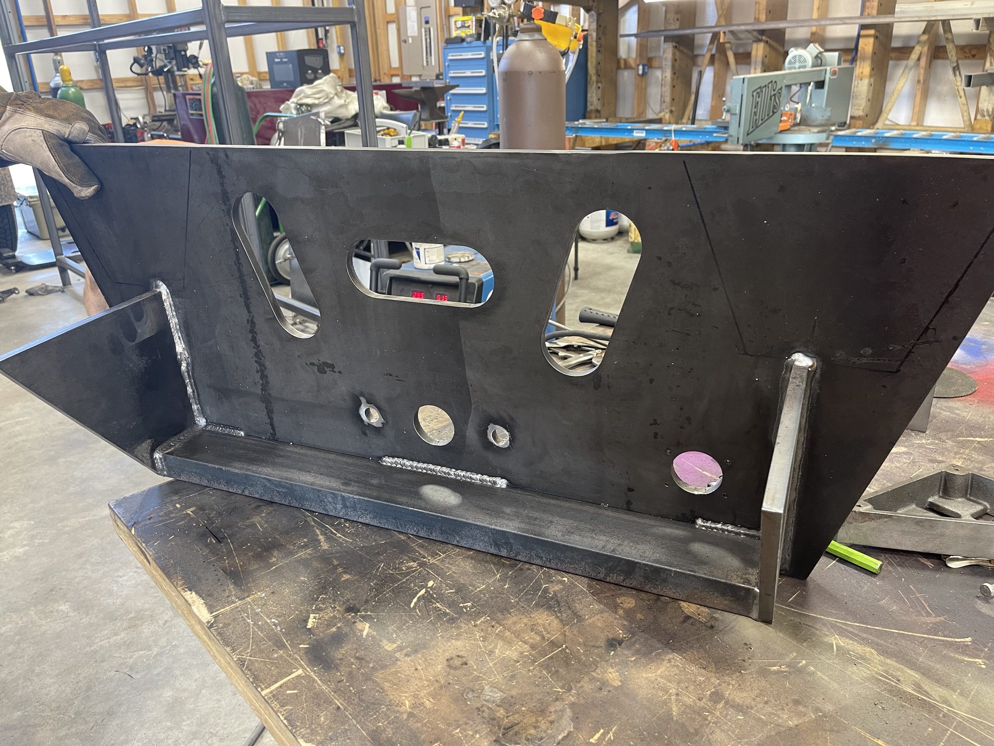 Welding bay at Primo Metal Works, with a mezzanine, jack stands, and racks of steel
