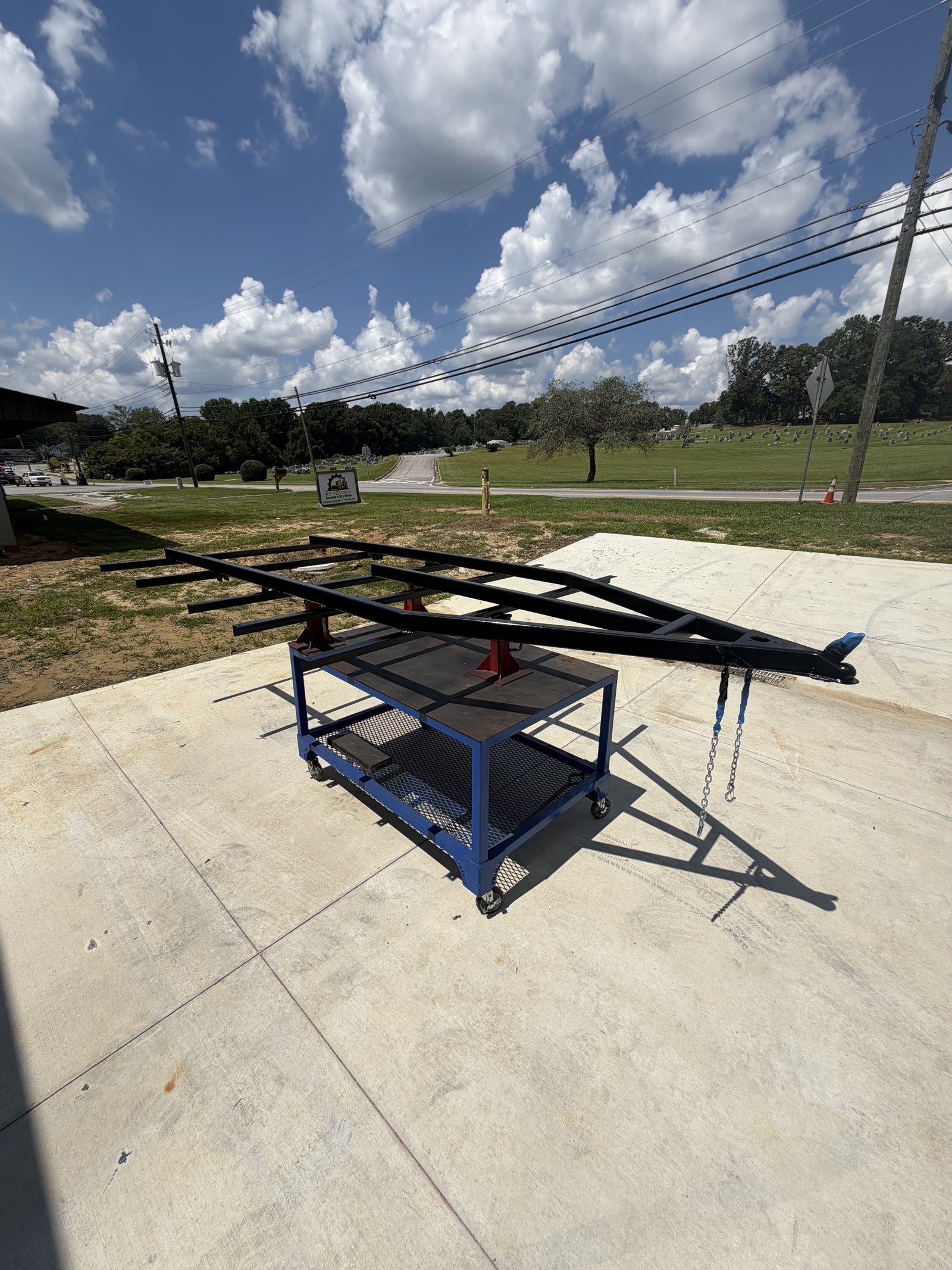 Welded steel trailer chassis upside down on sawhorses in the shop
